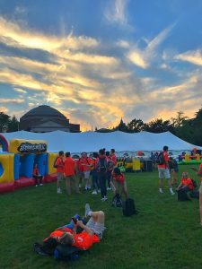 A large white tent is in the middle of the Syracuse University quad. Surrounding it are new students participating in Syracuse Welcome activities like inflatables.