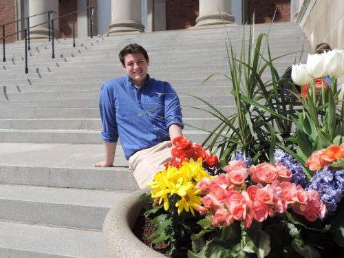 Brian Aitken poses on Hendricks Chapel Steps behind summer flowers.