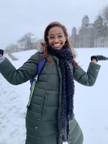 A student excitedly poses in front of a snowy Hall of Languages