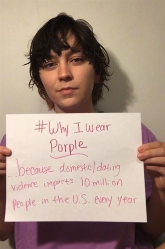 A student holds a paper sharing why they wear purple.