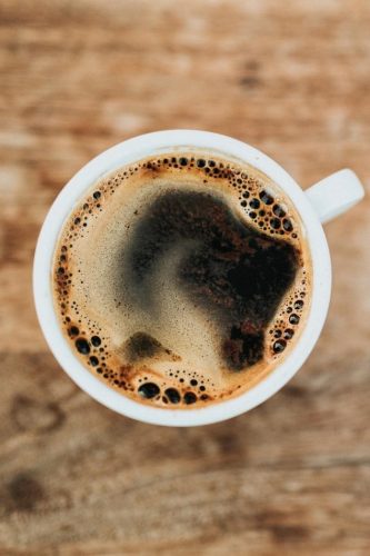 A birdseye view of a dark, foamy cup of coffee.