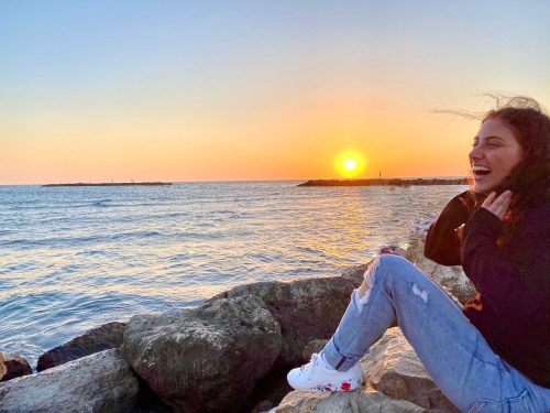 Rachel lounges on a rocky beach in Tel Aviv