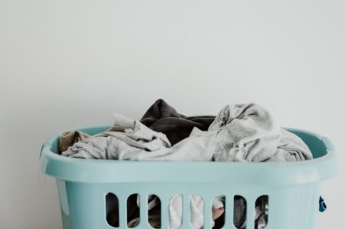 A blue laundry basket full of clothes. 