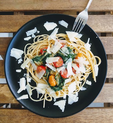 A plate of pasta with spinach, grape tomatoes and freshly grated parmesan. 