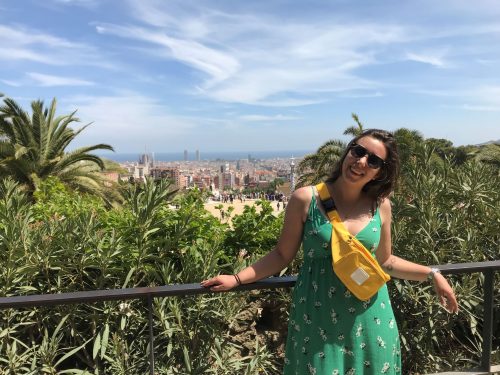 Maire in a green dress poses in front of the Barcelona skyline.