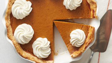 A birds eye view of a pumpkin pie with whipped topping dollops on top.