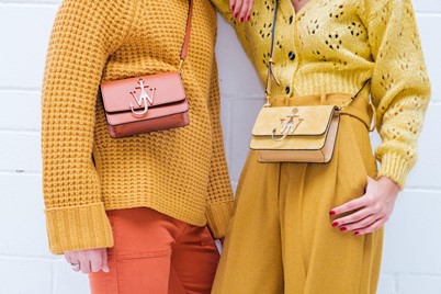 Two people wearing mustard tone outfits with cross body clutches.