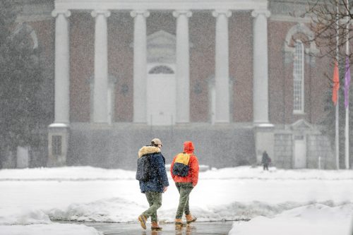 Two students walking in front of Hendricks Chapel in a snowstorm.
