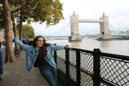 A young woman poses in front of the tower bridge while studying abroad in London.