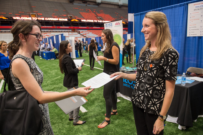 Student hands resume to recruiter during a career fair
