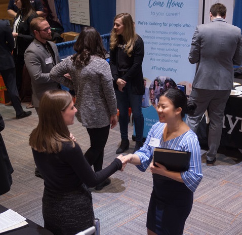 Student shakes hands with a recruiter during career fair