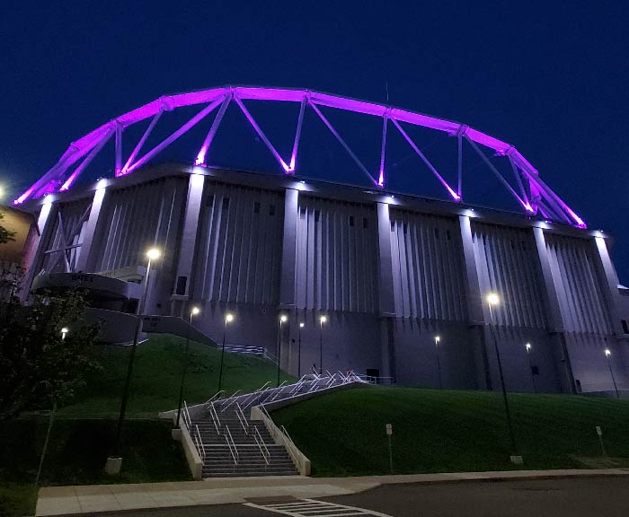 The JMA Wireless Dome lit purple at night.