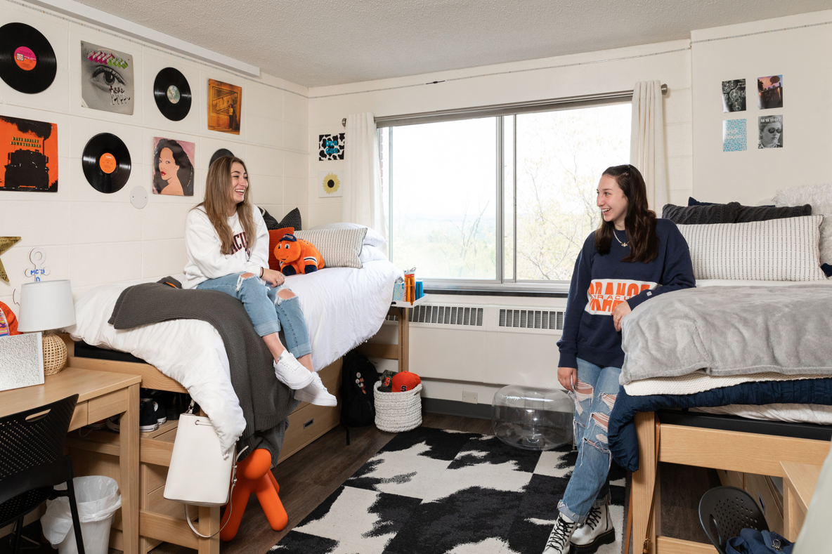 Two students laugh together in their dorm room.