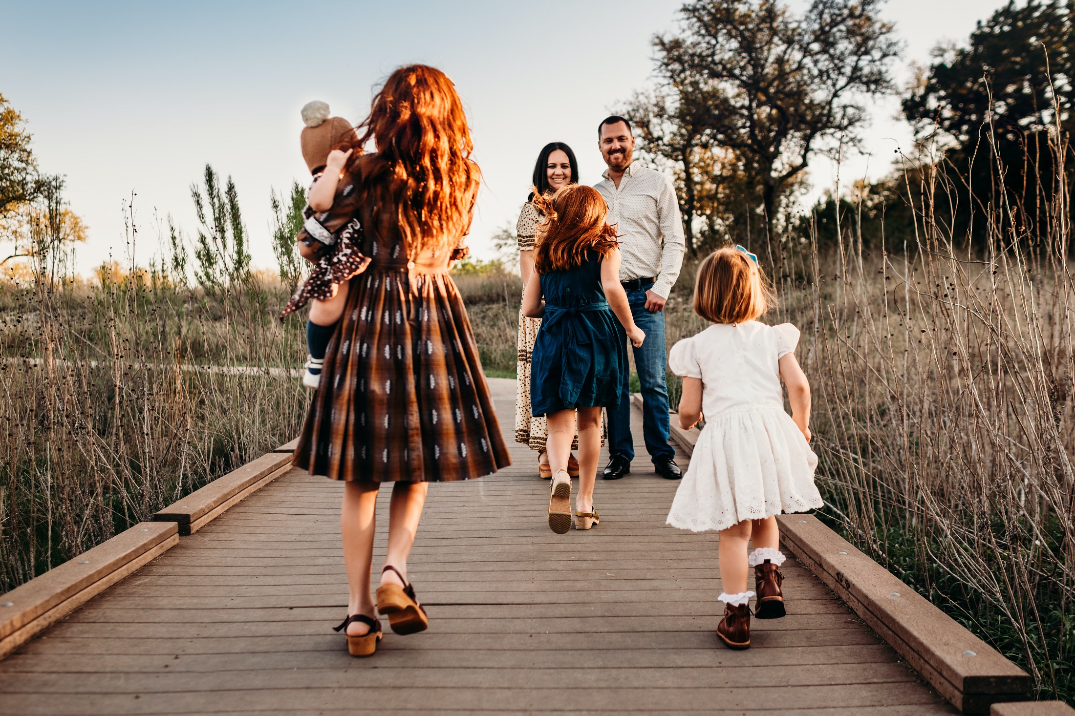 A family goes on a walk on a wooden path.