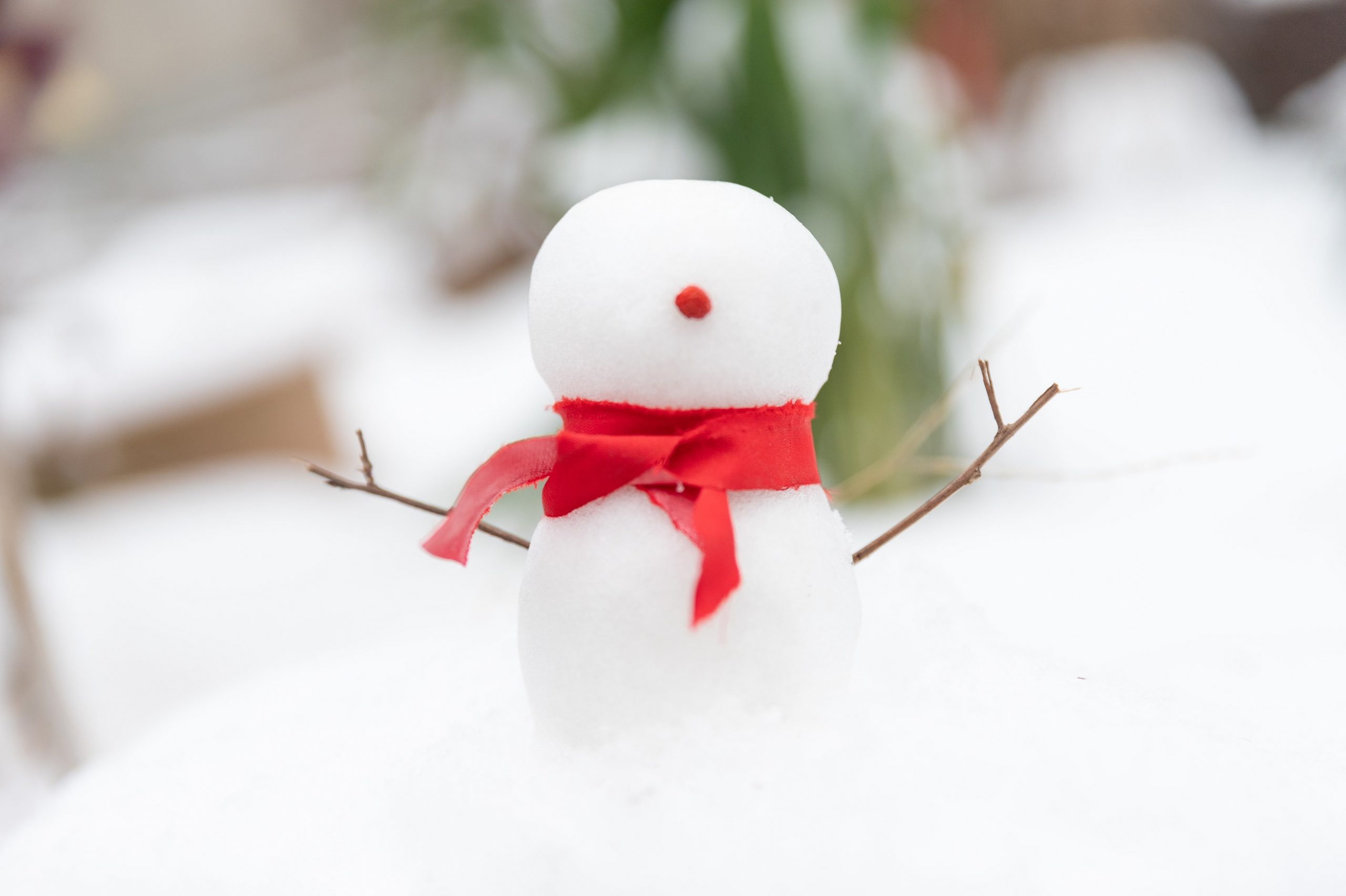 A small snowman with a red ribbon tied around its neck for a scarf