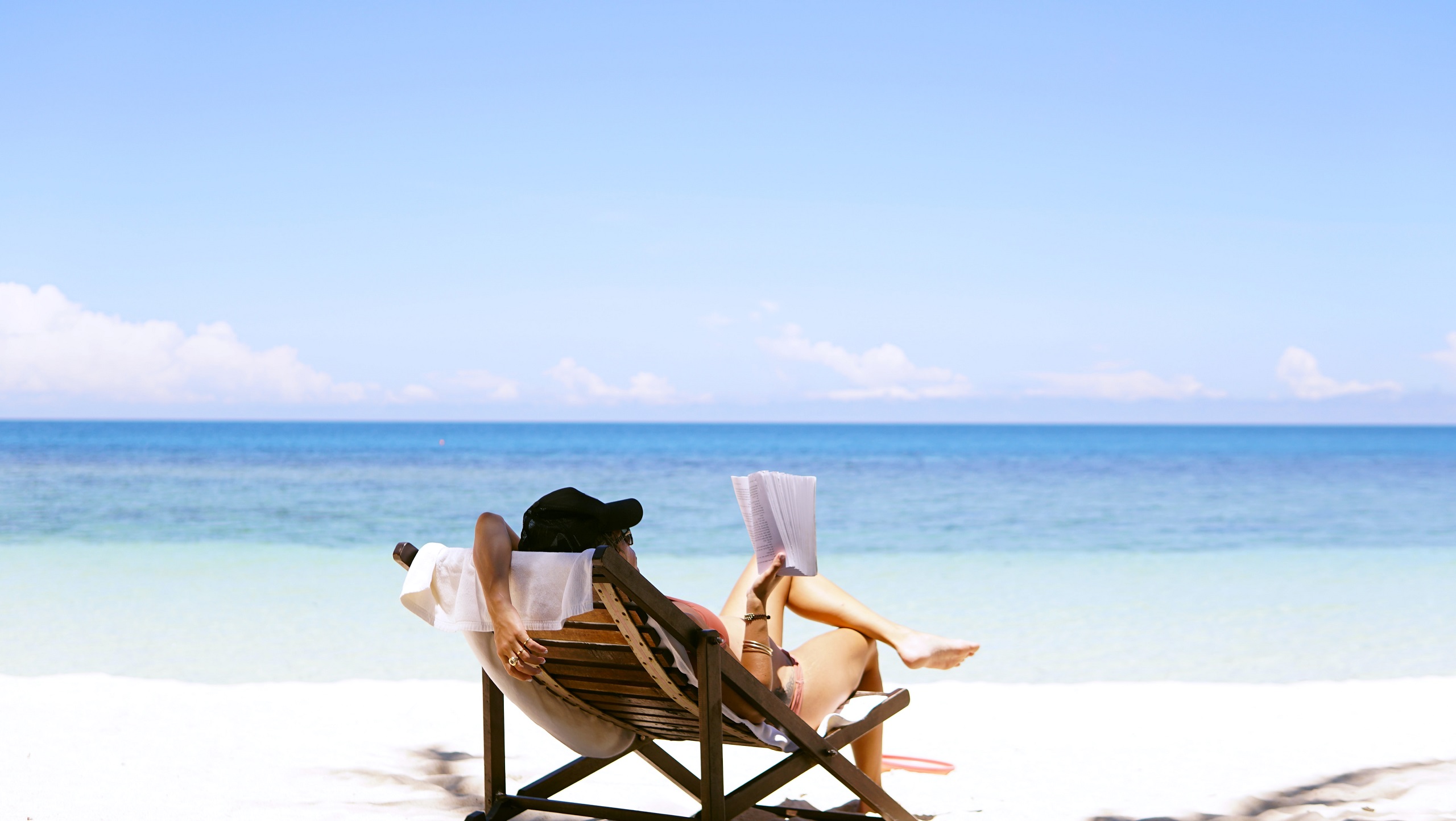 Woman lounges on a beach chair reading a book