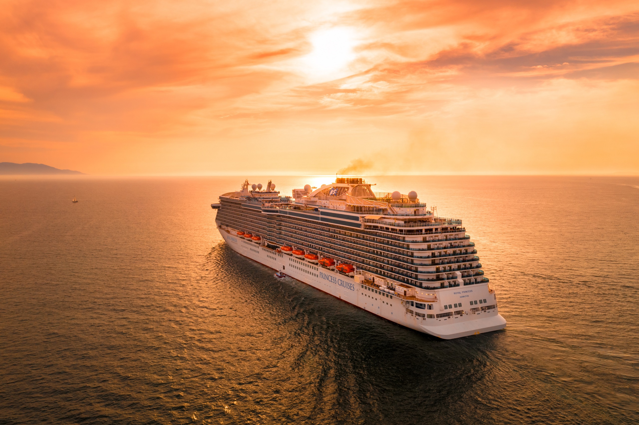 A cruise ships sails on the ocean at sunset