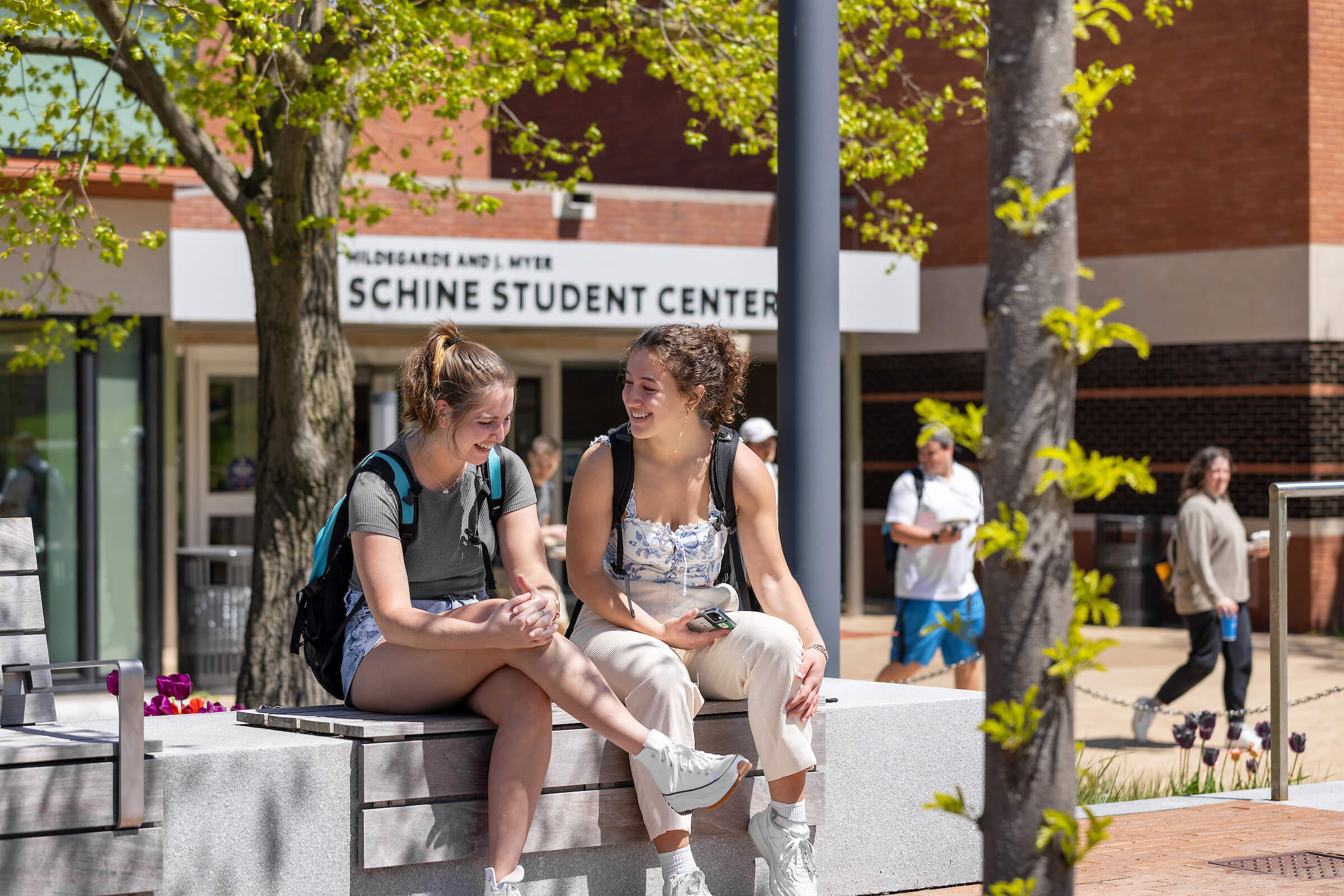 Two students talk and laugh outside Schine Student Center.
