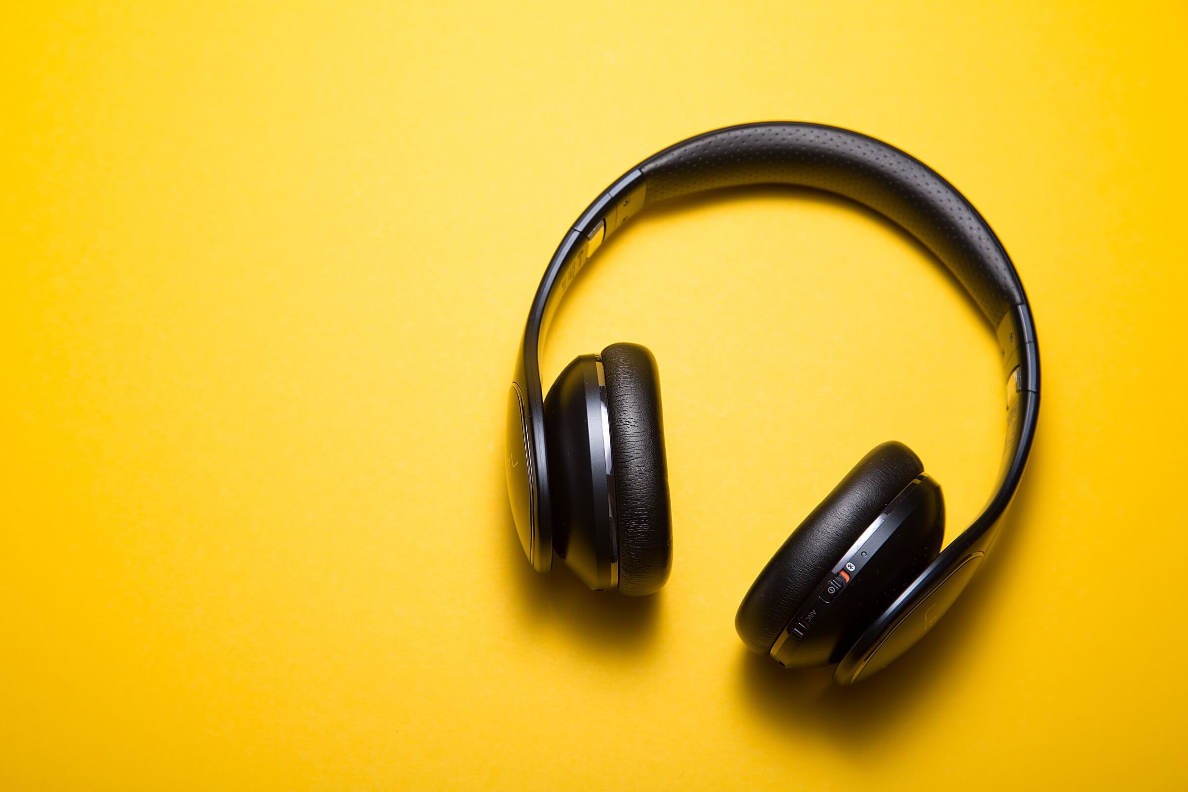 Black headphones lying on a yellow background