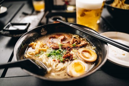 Someone cooks ramen in a skillet on a stove.