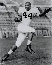 Black-and-white photo of Ernie Davis running with a football in his jersey with the number "44" across his chest.