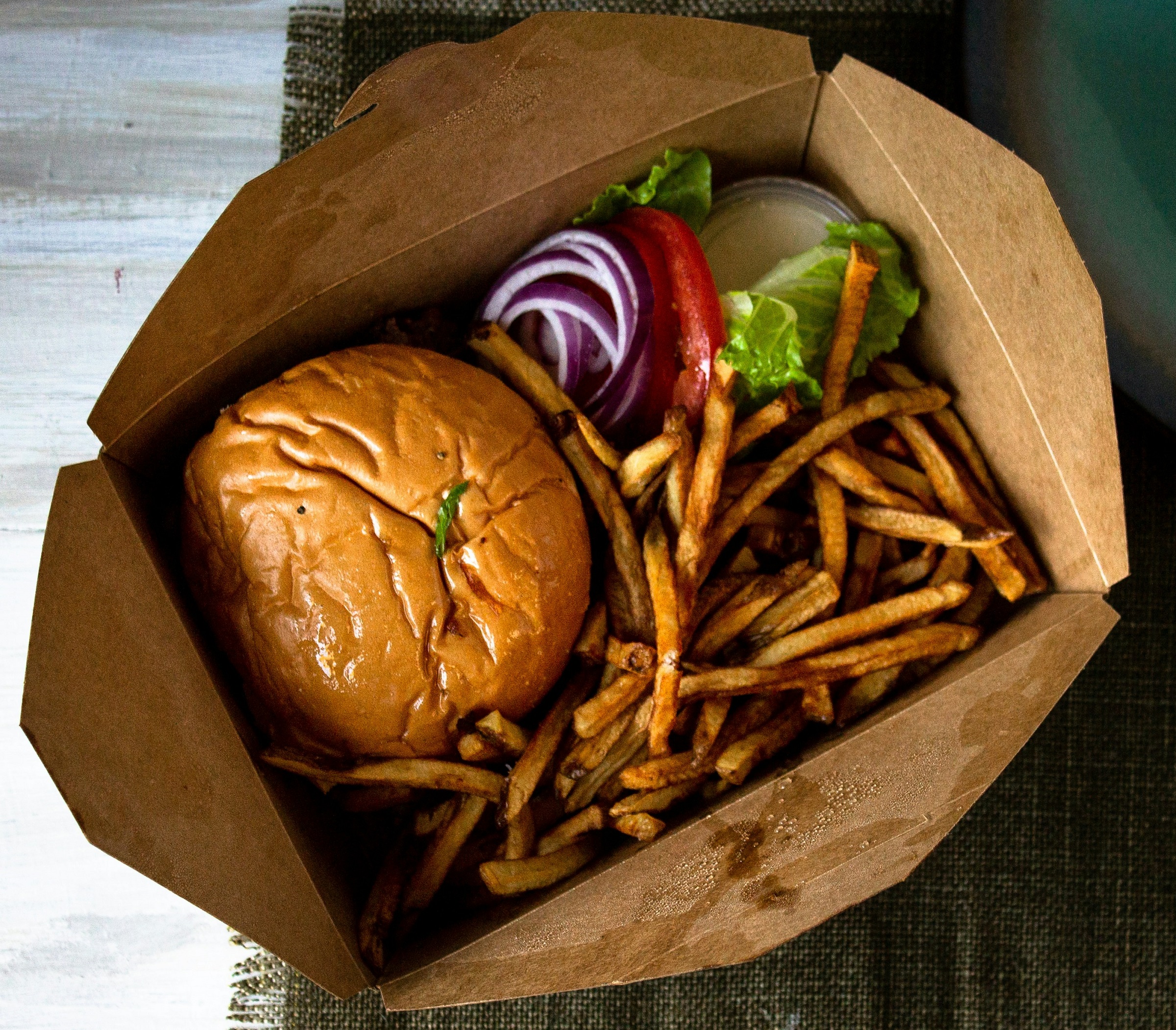 A burger and fries in a takeout box.