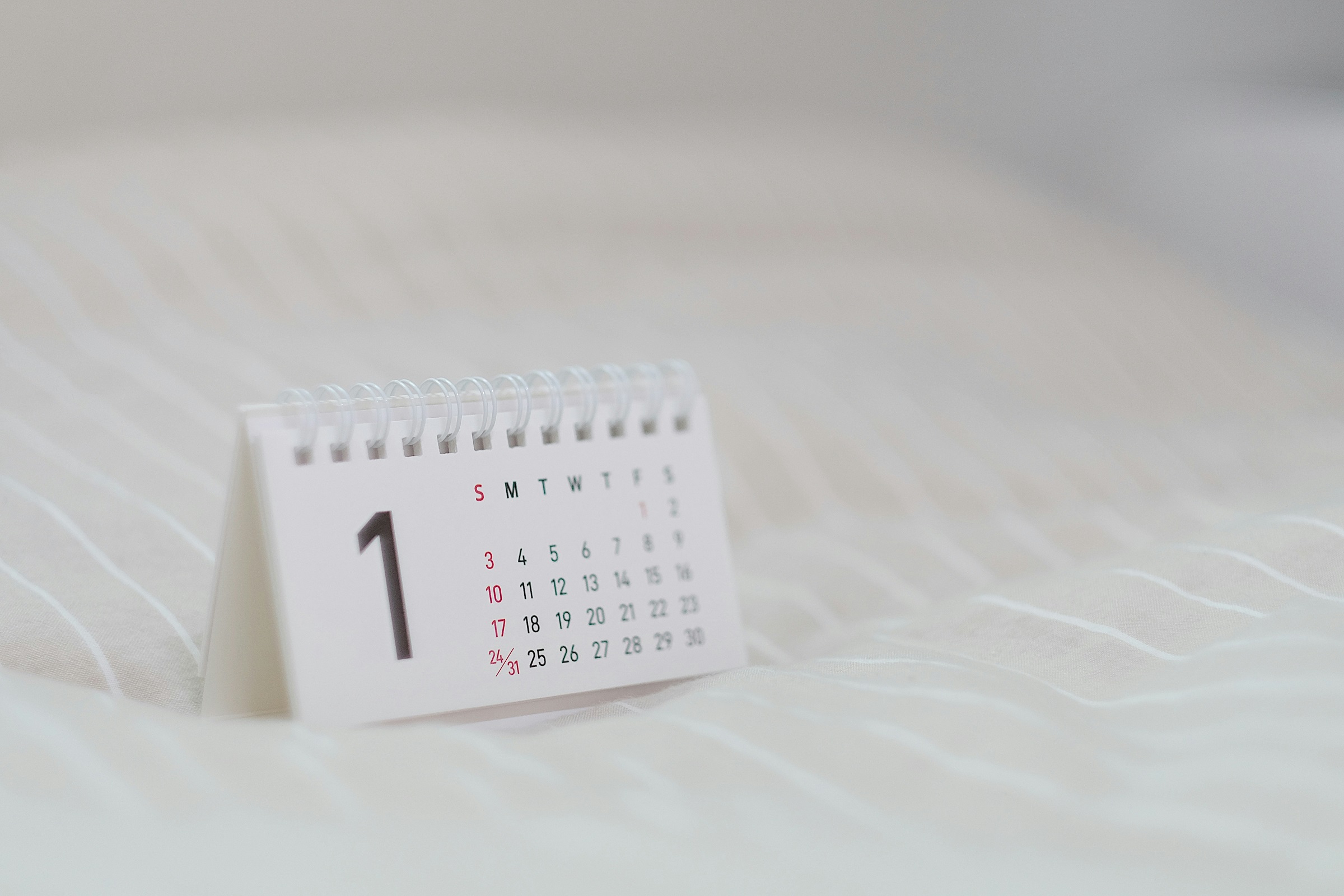 A small calendar sits on white sheets.