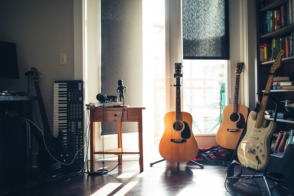 Music instruments lined up in a room. Visible are some guitars and a keyboard