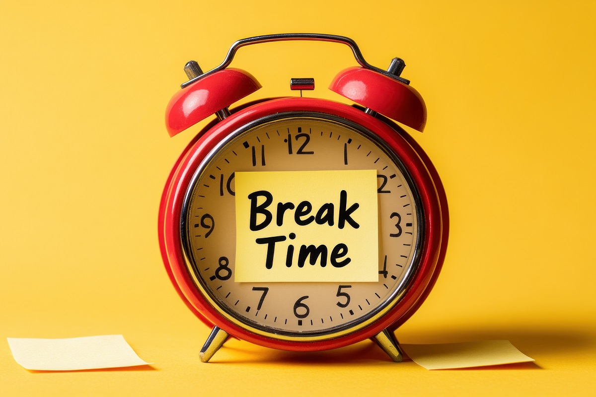 A red vintage alarm clock with a sticky note that says "Break Time" on its face