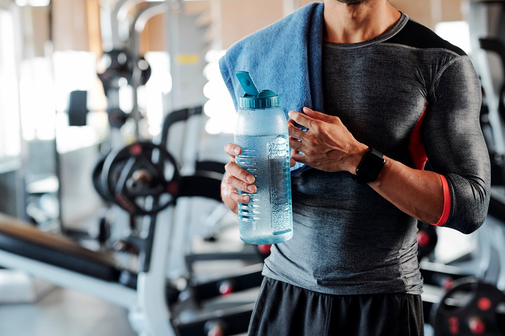 A man holds a water bottle while at the gym.