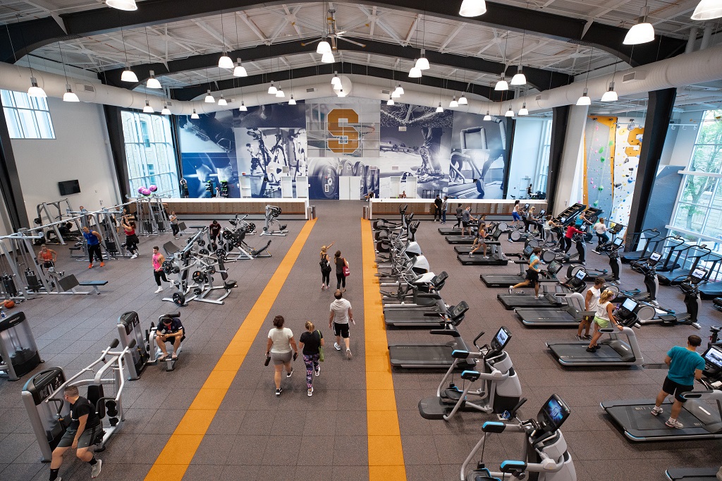 Students walking through the Barnes Center and using the gym equipment.