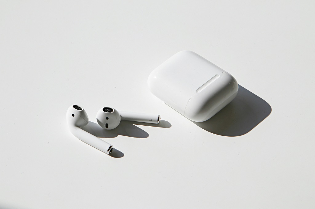 AirPods and their case on a white table.