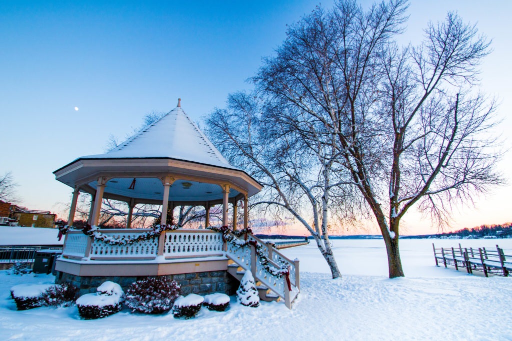 A gazebo in Skaneatles in winter at sunset; the entire area is covered in snow.