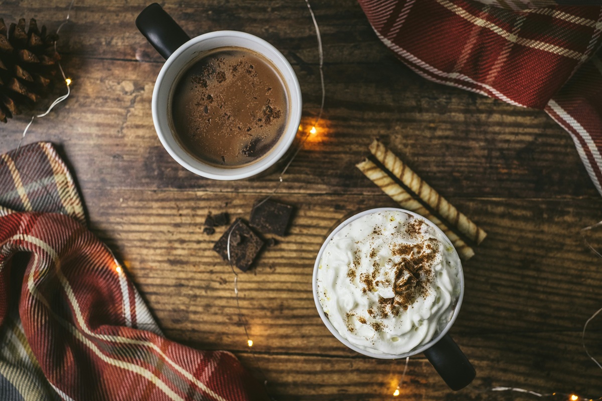Two mugs of hot chocolate on a wooden table.
