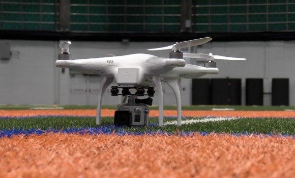 white drone with four props rests on floor of manley field house.