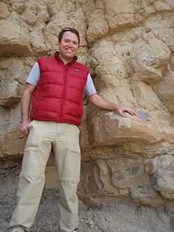 Christopher Junium in Colorado, posing with 94 million-year-old rock 