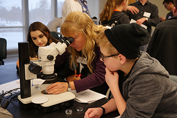 Associate Professor Kate Lewis adjusts a microscope for eighth- and ninth-graders during annual High School Biology Apprenticeship Day.