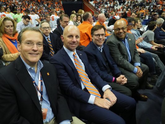 Enjoying Tuesday’s Syracuse-Iona men’s basketball game are (front row) Syracuse Director of Athletics John Wildhack ’80, Sean McDonough ’84, Bob Costas ’74 and Mike Tirico ’88, along with (second row) Beth Mowins G’90 and Sandy Montag ’85. (Photo by Michael J. Okoniewski)