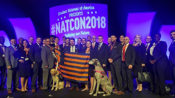 group of people holding SU flag in front of screen