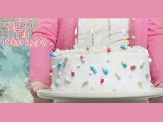 person holding decorated cake with "Next to Normal" logo at left