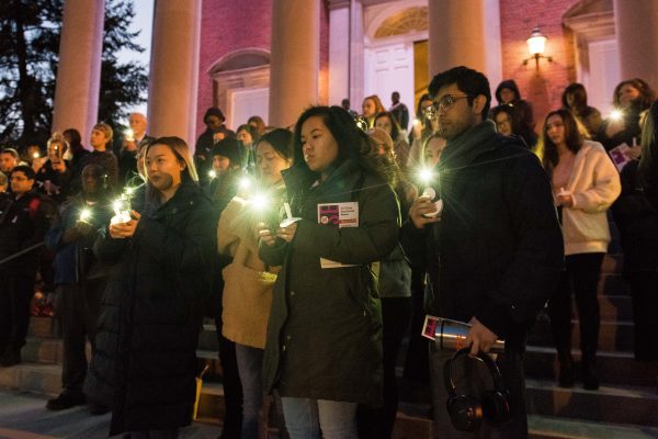 people standing in front of Hendricks Chapel holding phone lights