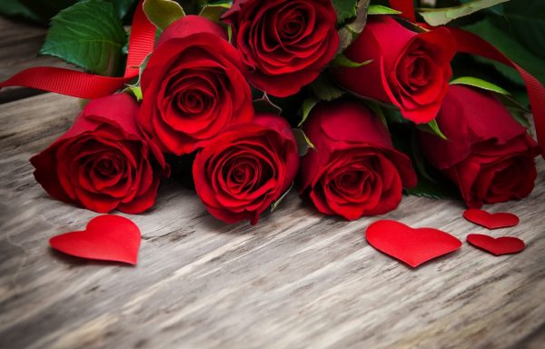 red roses with hearts on a wooden table