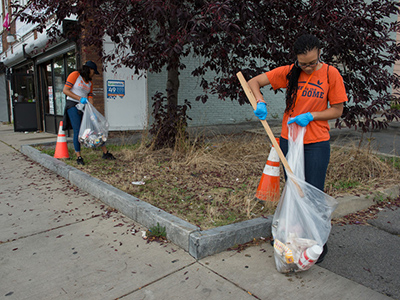 Two young people cleaning up trash on the street