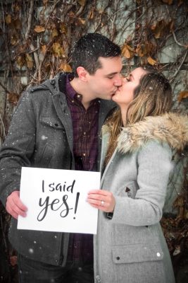 a man and woman kissing holding sign that says "I said yes!"