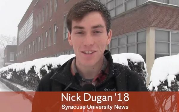 Nick Dugan stands outside womens building holding cuse cast microphone