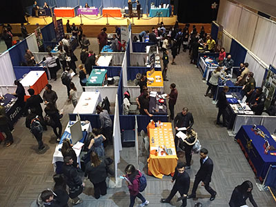 Students browse among tables with representatives at them.