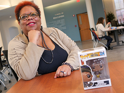Kal Alston at desk with figurine of character Shuri from "Black Panther"