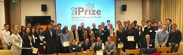 Competitors and judges at the RvD iPrize competition--dozens of people standing and sitting in front of a screen that read RvD Prize, School of Information Studies