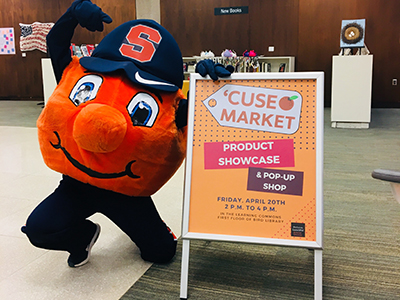 Otto showing off next to a sign for 'Cuse Market