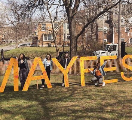 several people posing with giant letters that state Mayfest